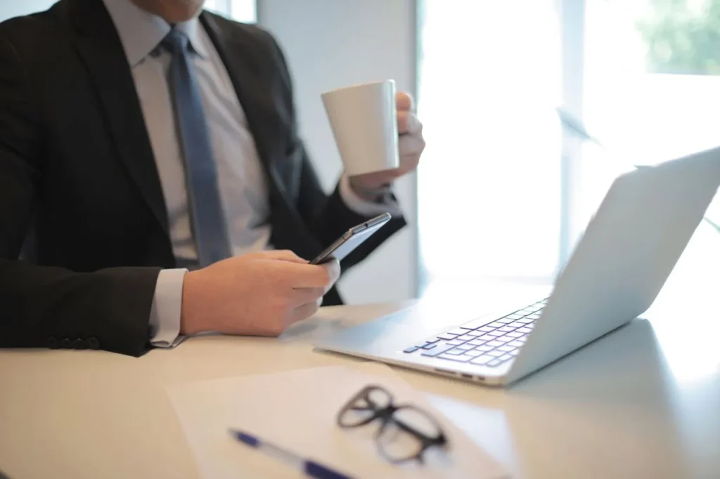 Homem de negócios com café e smartphone em escritório