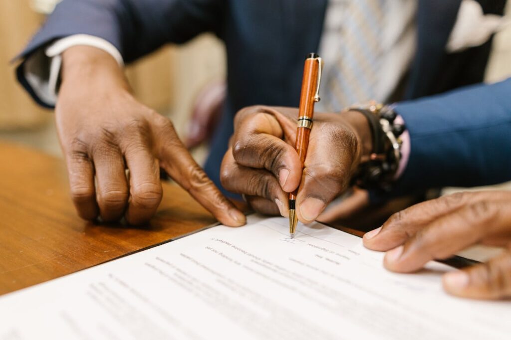 Mãos assinando um documento em uma mesa